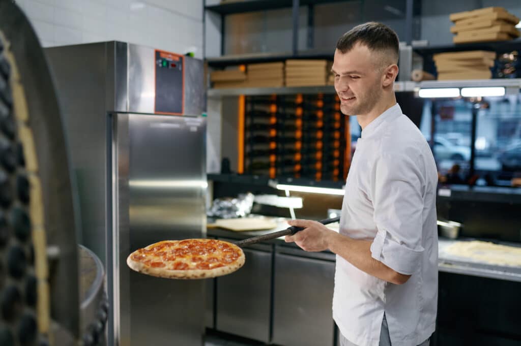 happy man working at pizza shop - Search Engine Marketing isn't just about reaching the globe. Local advertising is essential to reach untapped audiences in your backyard. - your wp guy - How can businesses effectively target local audiences through search engine marketing? 