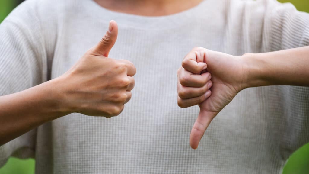 Closeup image of a woman making thumbs up and thumbs down hands sign