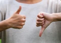 Closeup image of a woman making thumbs up and thumbs down hands sign